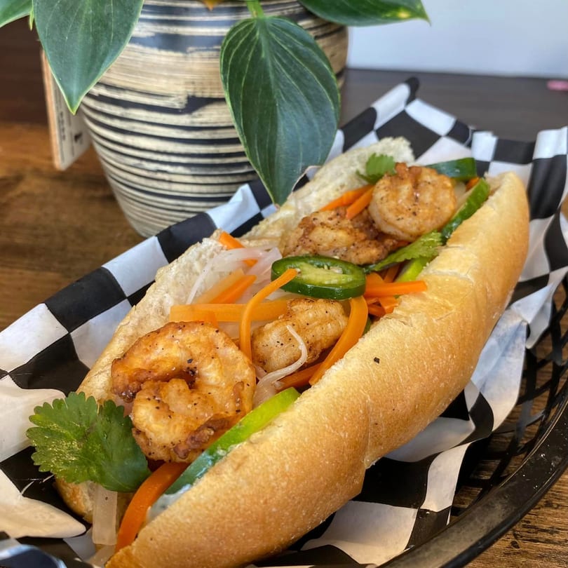 A Simply Boba shrimp banh mi sandwich with pickled vegetables and jalapeños in a basket.