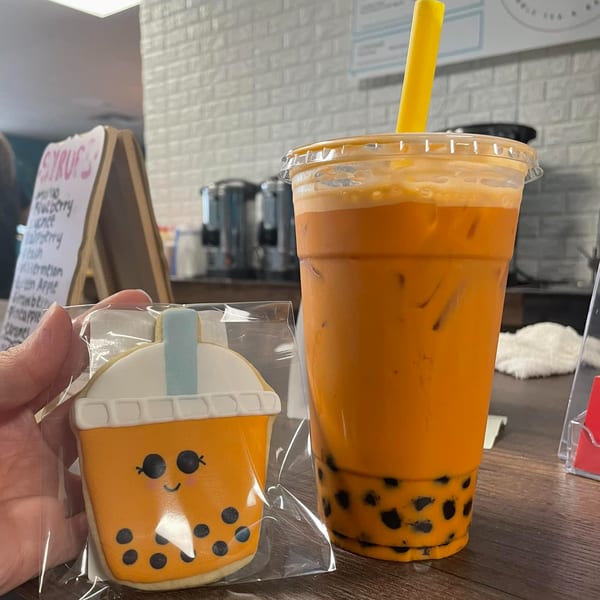 A Simply Boba Thai tea with boba pearls next to a boba cup-shaped cookie.